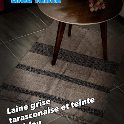 Tapis en Laine Tarasconnaise – Pièce Unique d'Artisanat d'Art** Succombez au charme authentique de ce tapis unique, entièrement tissé à la main à Toulouse sur un métier à bras traditionnel par l'artisane Line PARERA, fondatrice de l’Échoppe de Linette. Façonné en **laine cardée tarasconnaise** (filière française valorisée), il marie l'élégance brute d'un gris naturel à de superbes bandes graphiques bleu profond, teintées de manière écoresponsable à l'atelier. Un travail d'orfèvre aux motifs géométriques rythmés, sublimé par des finitions soignées en double nœuds. * **Dimensions :** 102 cm $\times$ 71 cm * **Composition :** 100% laine française (tarasconnaise) * **Temps de réalisation :** 6 heures de tissage méticuleux Une pièce de caractère durable, chaleureuse et écoresponsable pour sublimer votre intérieur.